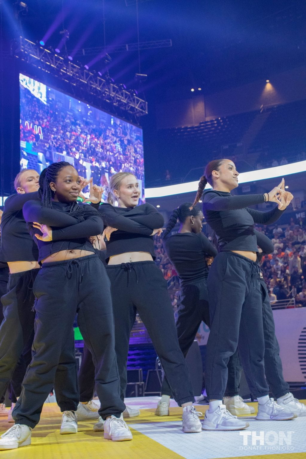 a group of diverse young women stand posing in a stage dressed in black