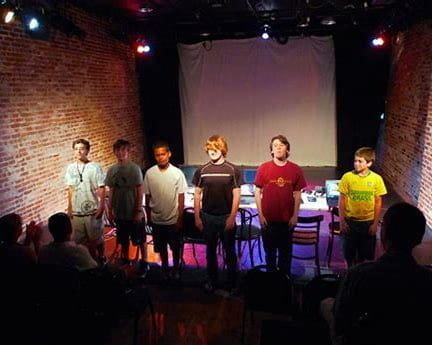 Six young children standing on improv stage.